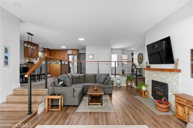 living area with stairway, a fireplace, wood finished floors, and a wealth of natural light