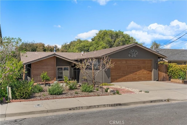 view of front facade with an attached garage, stucco siding, fence, and driveway
