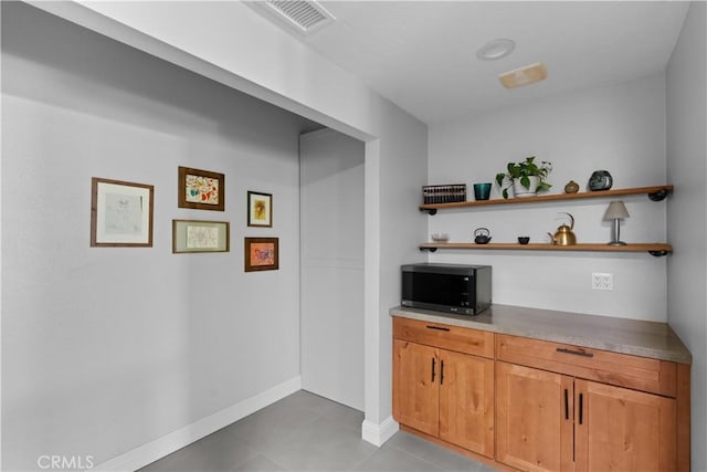 bar featuring baseboards, visible vents, and light tile patterned floors