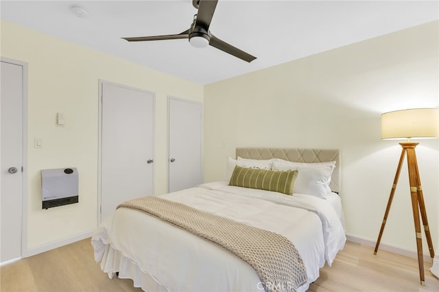 bedroom with a ceiling fan, baseboards, and light wood finished floors