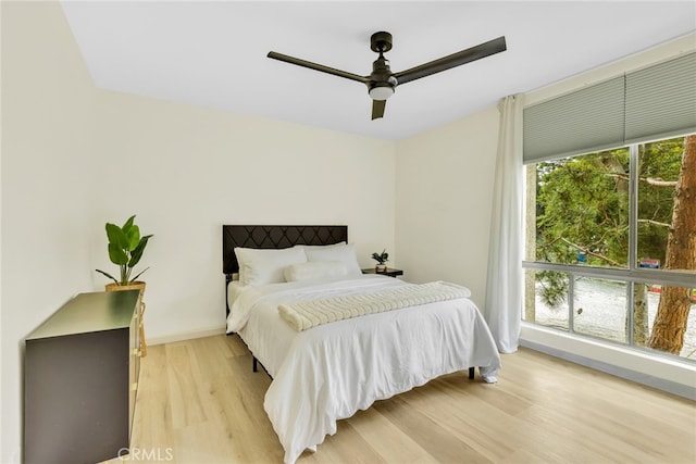 bedroom featuring baseboards, ceiling fan, and light wood-style flooring