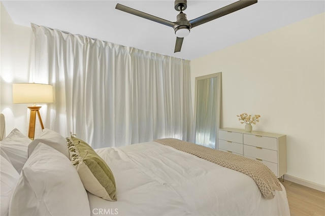bedroom with baseboards, ceiling fan, and light wood-type flooring