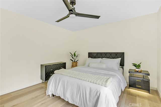 bedroom featuring baseboards, ceiling fan, and light wood-style flooring