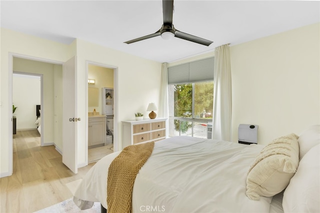 bedroom with light wood-style floors, ensuite bathroom, and a ceiling fan