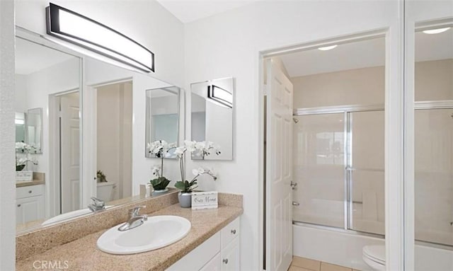 full bath featuring tile patterned flooring, toilet, vanity, and bath / shower combo with glass door