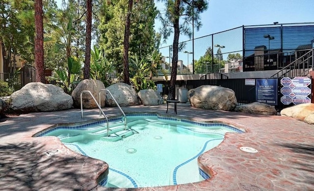 view of pool with a patio area, fence, and a hot tub