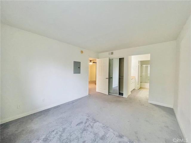 unfurnished bedroom featuring baseboards, electric panel, connected bathroom, visible vents, and light colored carpet