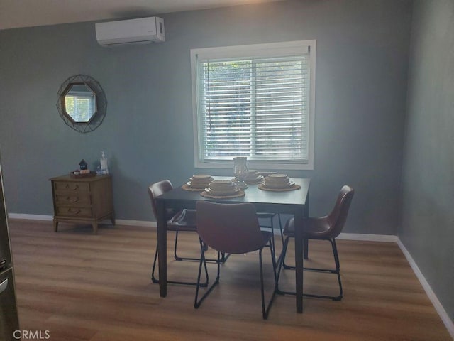 dining room with baseboards, wood finished floors, and an AC wall unit