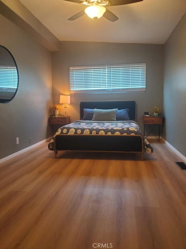 bedroom with baseboards, visible vents, wood finished floors, and a ceiling fan
