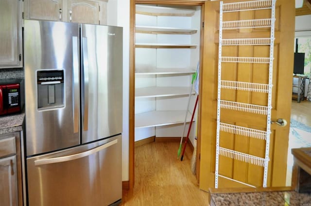 interior space featuring stainless steel fridge with ice dispenser, light countertops, baseboards, and light wood-type flooring