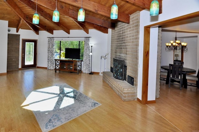 living area with an inviting chandelier, a brick fireplace, beam ceiling, wood ceiling, and wood finished floors