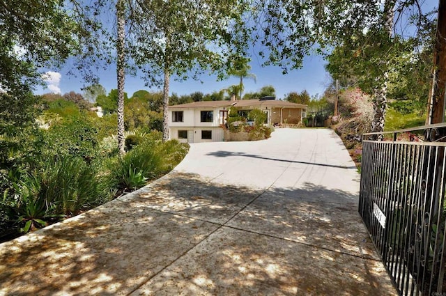 ranch-style house with concrete driveway and fence