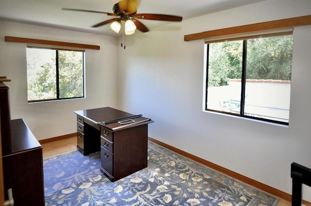 home office featuring dark wood finished floors, baseboards, a ceiling fan, and plenty of natural light
