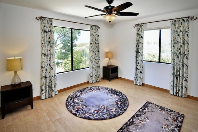 living area with ceiling fan, baseboards, and wood finished floors