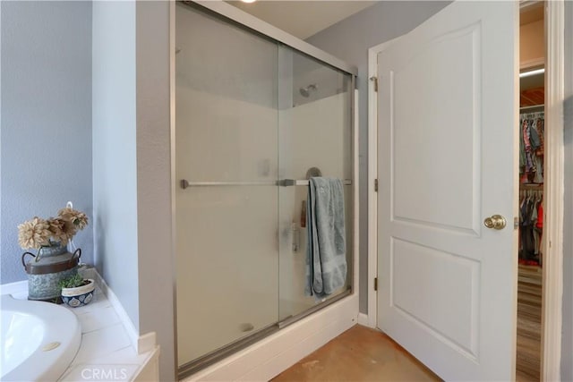 bathroom featuring a stall shower and a walk in closet