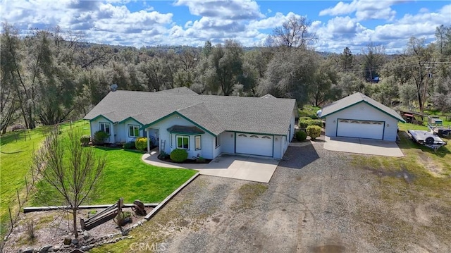 single story home with driveway, fence, a front lawn, and a forest view