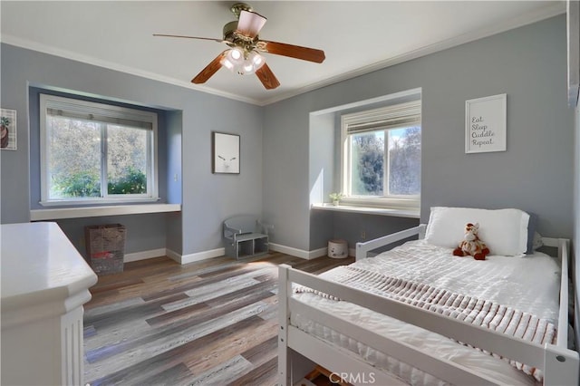 bedroom featuring ornamental molding, baseboards, multiple windows, and wood finished floors