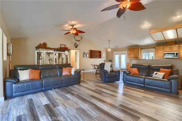 living room featuring baseboards, lofted ceiling, light wood-style flooring, and ceiling fan