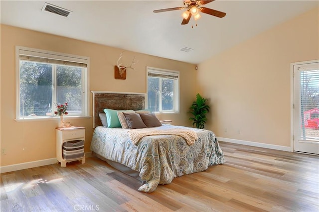 bedroom with multiple windows, visible vents, wood finished floors, and lofted ceiling