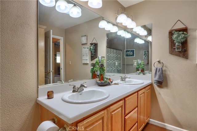 full bath featuring double vanity, a textured wall, and a sink
