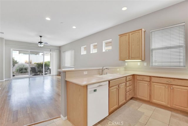 kitchen featuring open floor plan, light brown cabinetry, a sink, dishwasher, and a peninsula