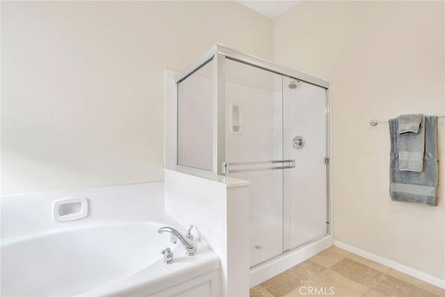 bathroom featuring a bath, baseboards, and a stall shower
