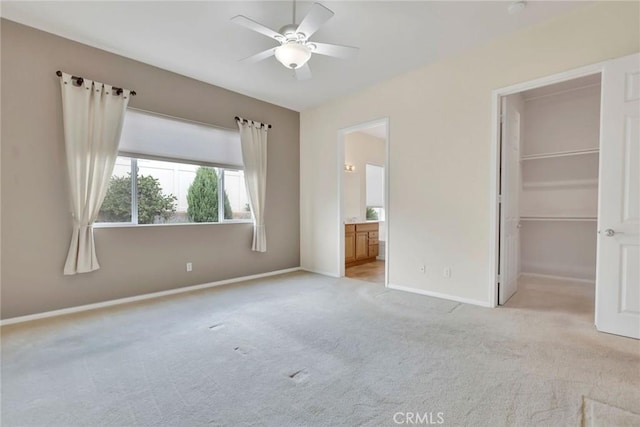 unfurnished bedroom with a walk in closet, light colored carpet, baseboards, ensuite bath, and a closet