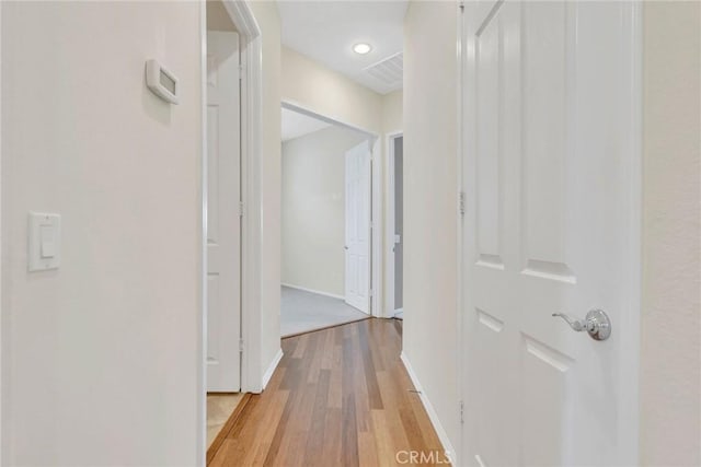 hallway featuring baseboards, visible vents, and light wood-style floors