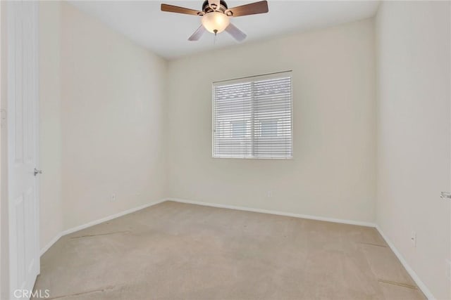 spare room featuring baseboards, light colored carpet, and ceiling fan