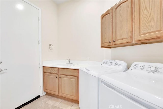 laundry room with light tile patterned flooring, washing machine and dryer, cabinet space, and a sink