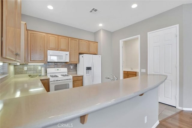 kitchen with light countertops, light brown cabinets, white appliances, visible vents, and decorative backsplash