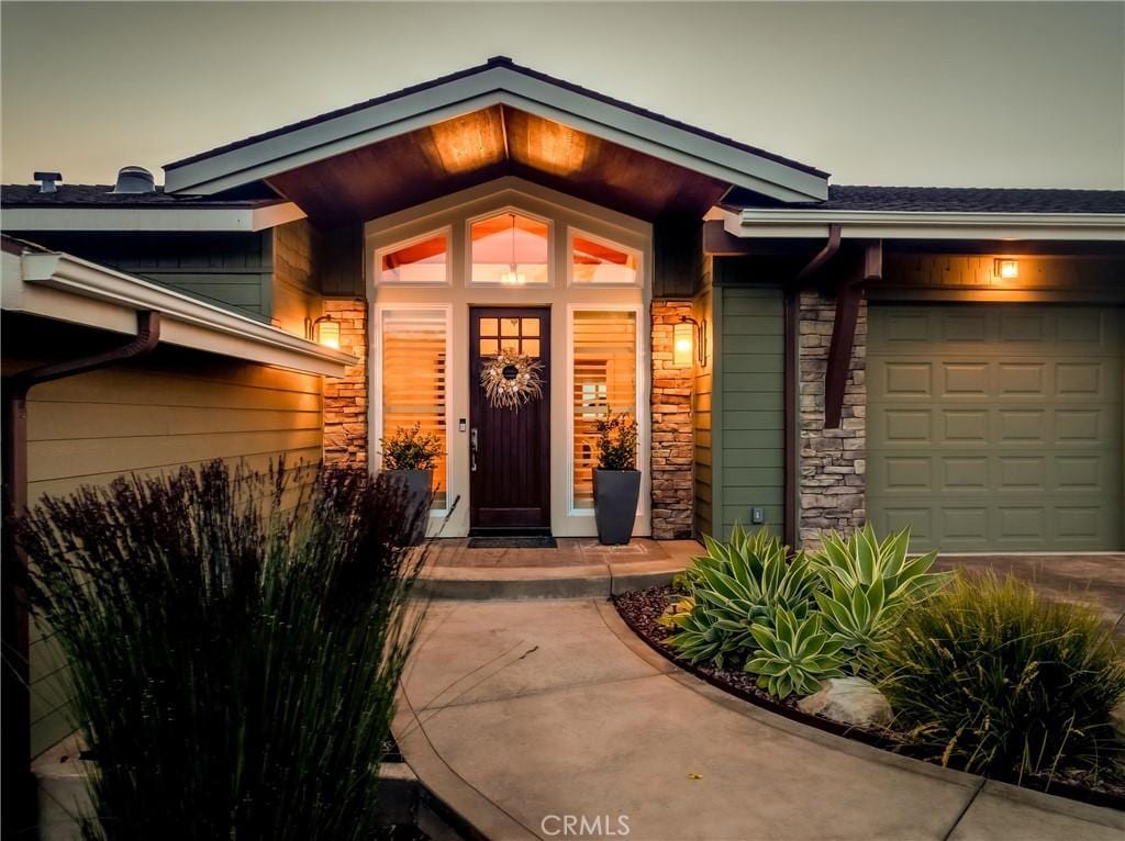 doorway to property featuring stone siding, concrete driveway, and a garage