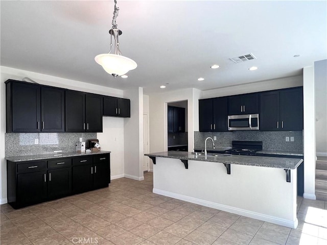 2866 S Via Belamaria, Ontario, CA 91762 - kitchen with dark stone counters, decorative backsplash, a breakfast bar area, range, and stainless steel microwave