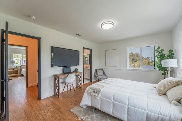 bedroom featuring visible vents, wood finished floors, and ensuite bath