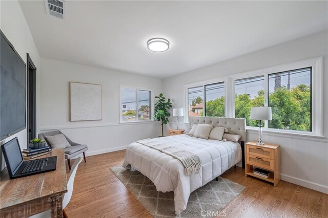 bedroom featuring baseboards, wood finished floors, and visible vents
