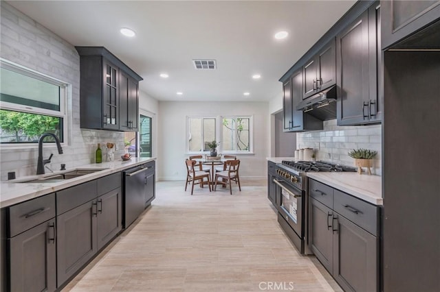 kitchen with backsplash, visible vents, appliances with stainless steel finishes, a sink, and under cabinet range hood