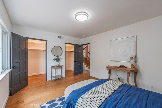 bedroom featuring baseboards, visible vents, light wood finished floors, and a spacious closet