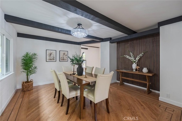 dining space with baseboards, beam ceiling, and wood finished floors