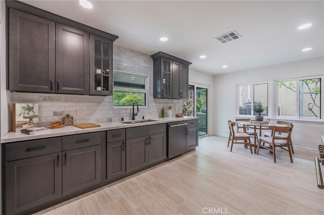 kitchen featuring a sink, light countertops, decorative backsplash, stainless steel dishwasher, and visible vents