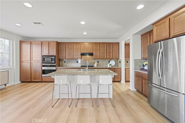 32177 Clear Springs Dr, Winchester, CA 92596 - kitchen with appliances with stainless steel finishes, under cabinet range hood, brown cabinets, light wood-type flooring, and recessed lighting
