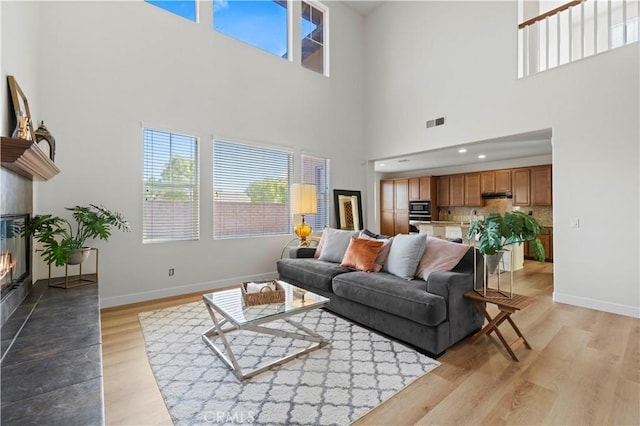 32177 Clear Springs Dr, Winchester, CA 92596 - living area with a glass covered fireplace, light wood-type flooring, plenty of natural light, and a towering ceiling