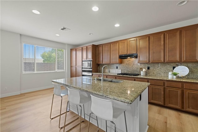 32177 Clear Springs Dr, Winchester, CA 92596 - kitchen with stainless steel appliances, under cabinet range hood, light wood-style flooring, backsplash, and light stone countertops