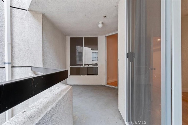 bathroom featuring a textured ceiling, concrete floors, and a textured wall