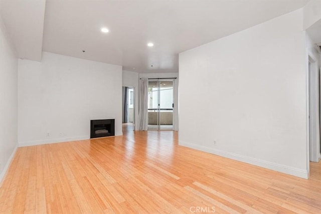 unfurnished living room featuring light wood-style flooring, a fireplace, baseboards, and recessed lighting