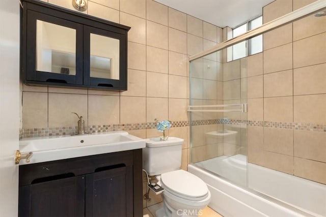 bathroom featuring tile walls, tasteful backsplash, toilet, vanity, and enclosed tub / shower combo