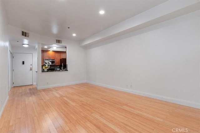unfurnished living room with light wood-type flooring, baseboards, and recessed lighting