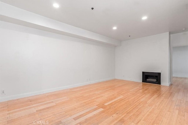 unfurnished living room featuring light wood finished floors, a fireplace, recessed lighting, and baseboards