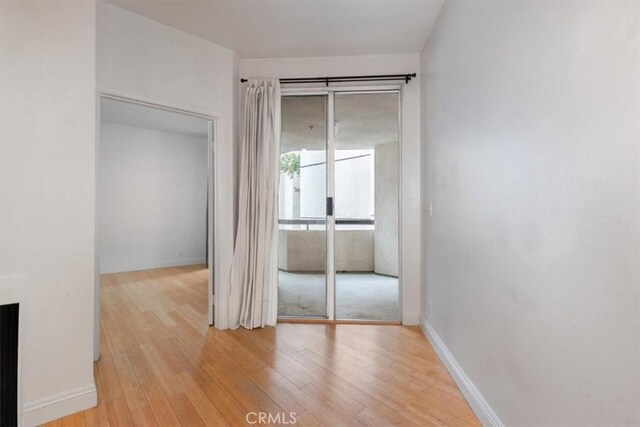 hallway featuring light wood-style flooring and baseboards