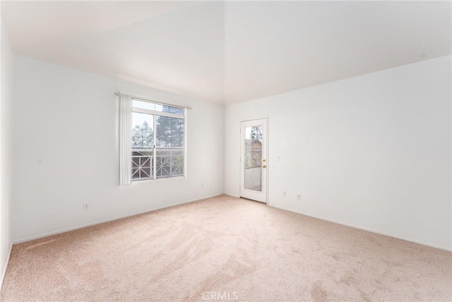 empty room featuring baseboards, high vaulted ceiling, and light carpet