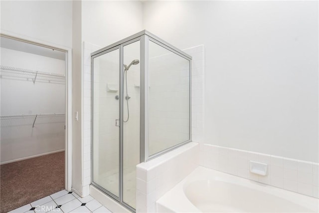bathroom featuring a stall shower, a walk in closet, and a bath